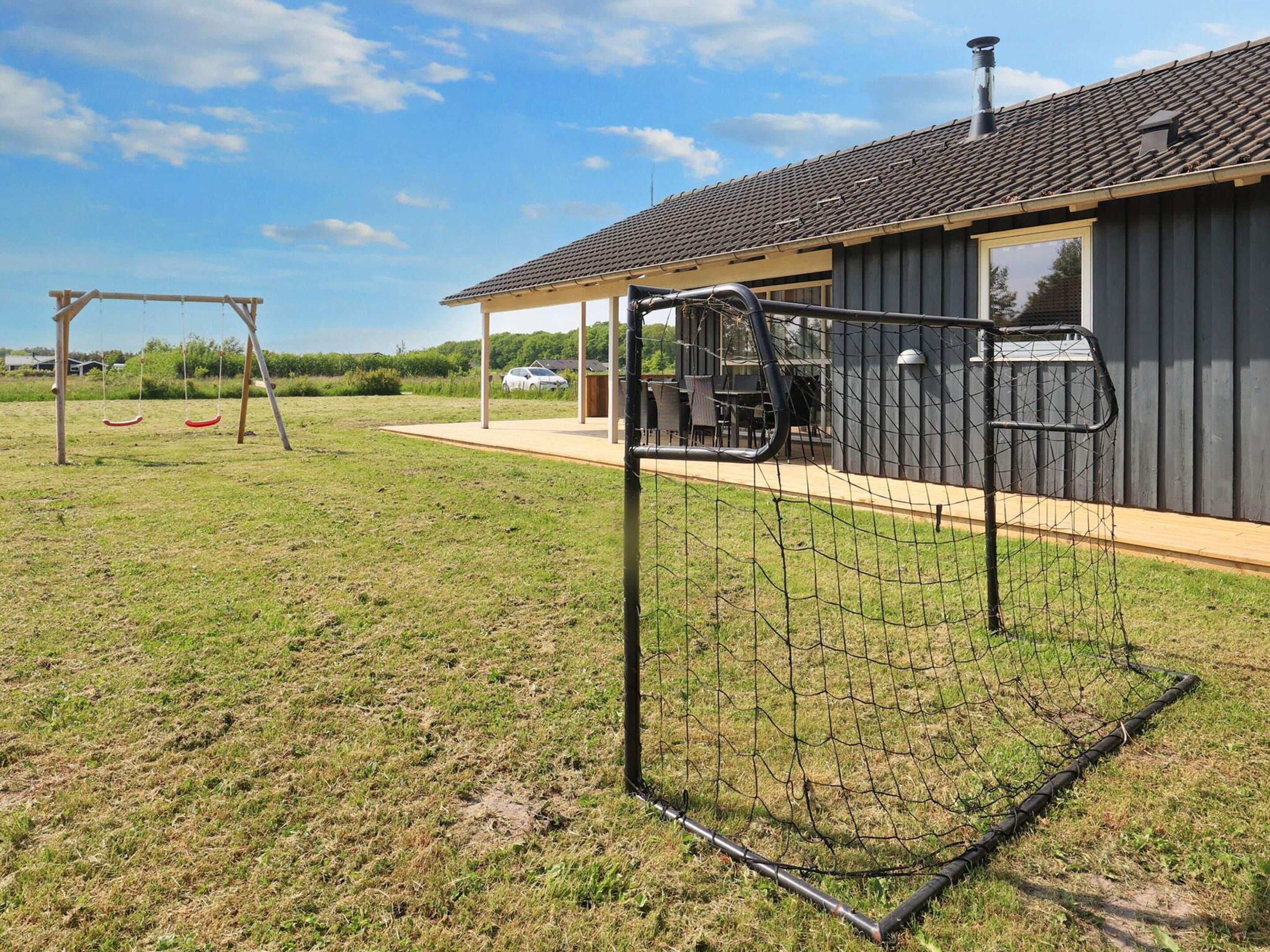 A residential property with a fenced backyard, a covered patio, and a swing set.