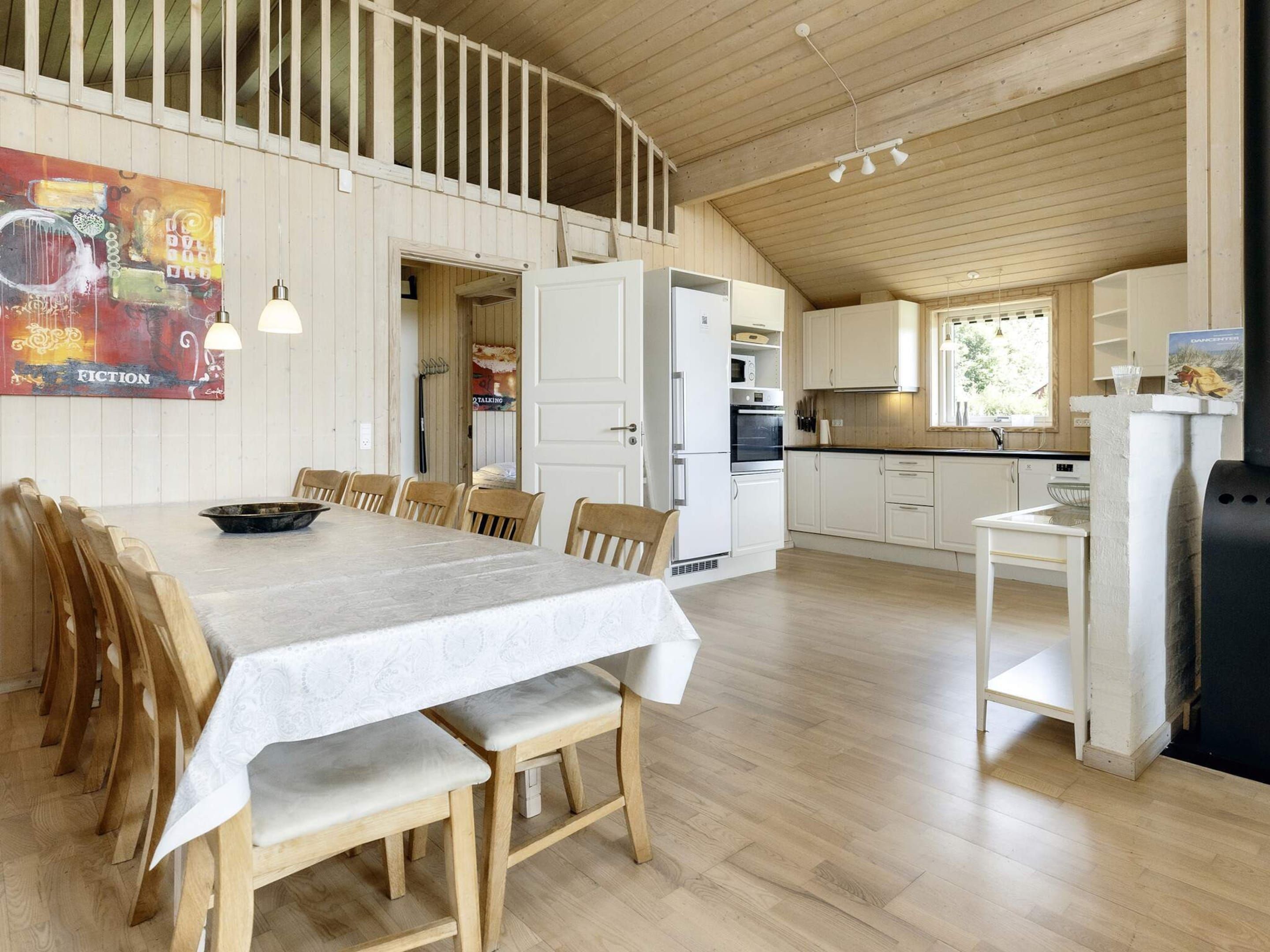 A spacious kitchen with white cabinets, a dining area with a table and chairs, and a loft bedroom with a wooden ceiling.