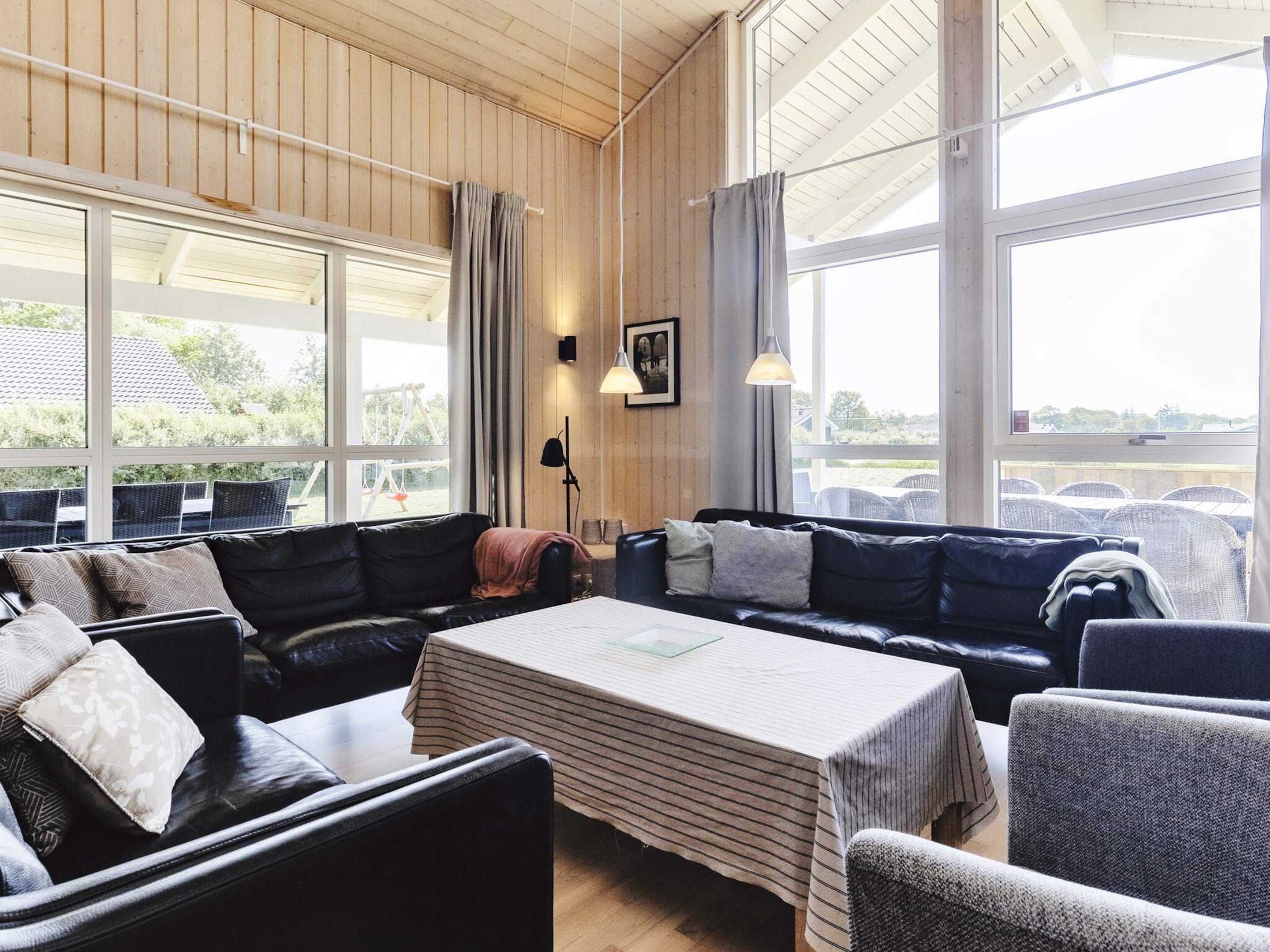 A cozy lounge area with leather sofas, a striped table, and large windows offering a view of the outdoors.