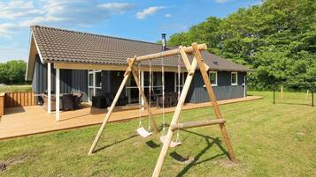 A wooden swing set in a backyard with a house in the background.