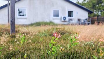 Une maison de plain-pied avec un toit en pente, une cheminée bien visible et un petit garage attenant.