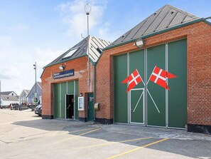 A brick building with green double doors, two Danish flags, and a sign reading "SOVEREIN KYSTREDNINGSGJENESTEN". - 7 Person Holiday Home in Thisted (Thisted)