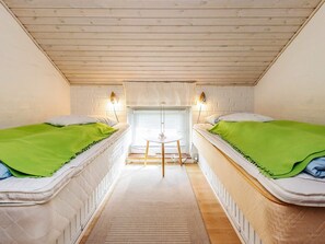 A small, cozy room with two beds, a small table, and a window with blinds. - 7 Person Holiday Home in Thisted (Thisted)