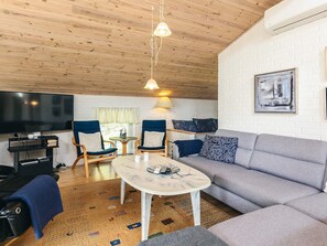A living room with a sofa, two armchairs, a coffee table, a TV, and a fireplace.