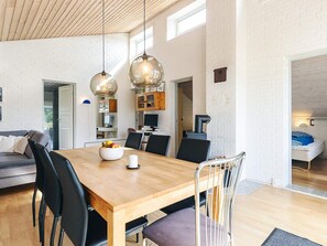 A spacious dining area with a wooden table, black chairs, and a bowl of fruit.