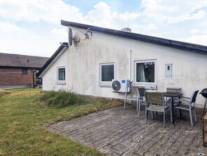 A house with a brick exterior, a satellite dish, and a patio with chairs and a table.