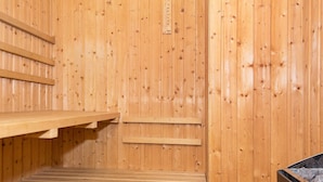 A sauna with wooden benches and a metal container, likely for water or steam. - 6 Person Holiday Home in Henne (Henne)