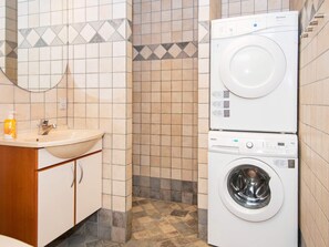 Compact laundry room with a washer, dryer, sink, and mirror.