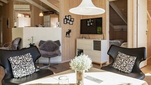 A modern, well-lit room with a wooden ceiling, a dining table with chairs, a sofa, a TV, and a kitchenette. - Luxury Retreat Near Beach - By Traum Ferienwohnungen (Otterup)