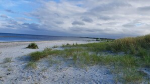 A beach with a dune and a vehicle in the distance. - 4 Person Holiday Home in Jerup-by Traum (Jerup)