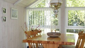 A dining area with a wooden table and chairs, a hanging light fixture, and a window with a view of greenery. - 4 Person Holiday Home in Jerup-by Traum (Jerup)