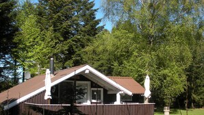 A small cabin with a sloped roof, a chimney, and a porch with a white umbrella. - 4 Person Holiday Home in Jerup-by Traum (Jerup)