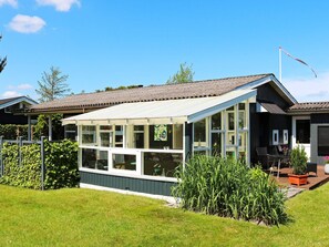 Ett hus med en inglasad veranda, ett husnummer 101 och en trädgård med växter.