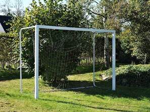Ett fotbollsmål på en gräsyta med träd och en byggnad i bakgrunden.