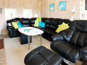 Un salon avec un ensemble de canapés en cuir noir, une table basse blanche et un tapis beige.