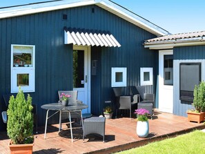 A blue building with a patio area featuring wicker furniture and potted plants.