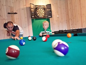A billiards table with balls and a dartboard in the background. - 5 Star Holiday Home in Sydals (Sydals)