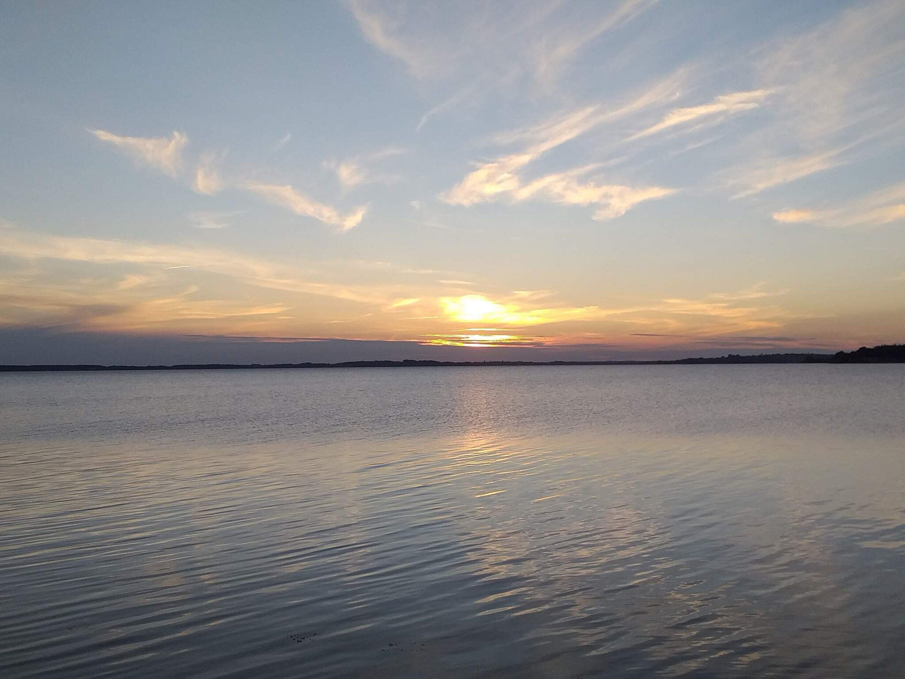 A calm body of water reflecting the sky during sunset.