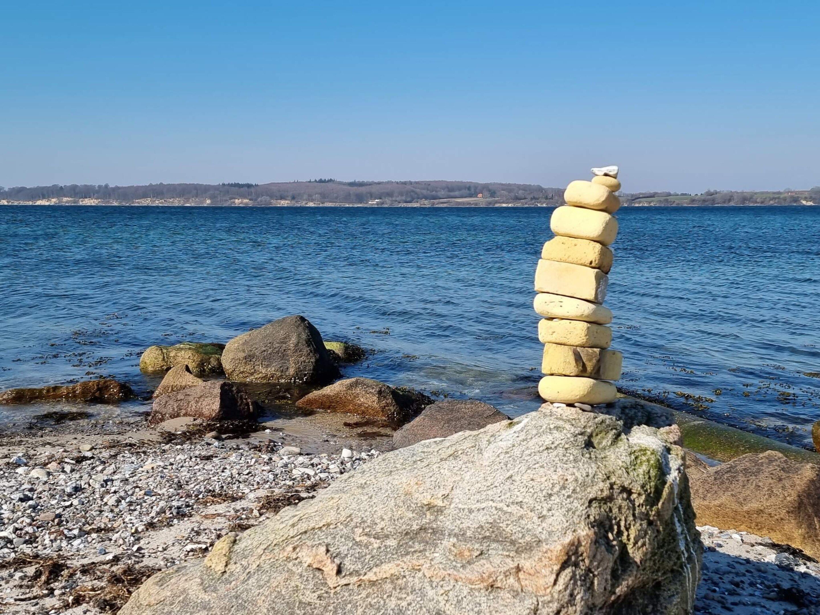Ein Steinhaufen an einem Gewässer unter blauem Himmel.