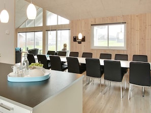 A modern dining area with a long table, black chairs, and a counter with a blue tray. - 5 Star Holiday Home in Sydals (Sydals)