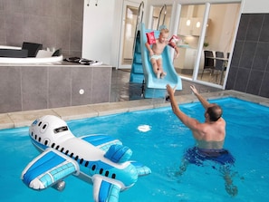 A swimming pool with a slide, a child on the slide, and an inflatable pool float. - 5 Star Holiday Home in Sydals (Sydals)