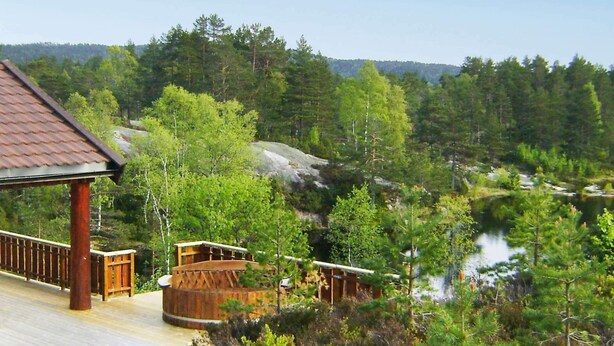 A wooden deck with a view of a forest and a river. - 9 Person Holiday Home in Bjelland (Lindesnes)