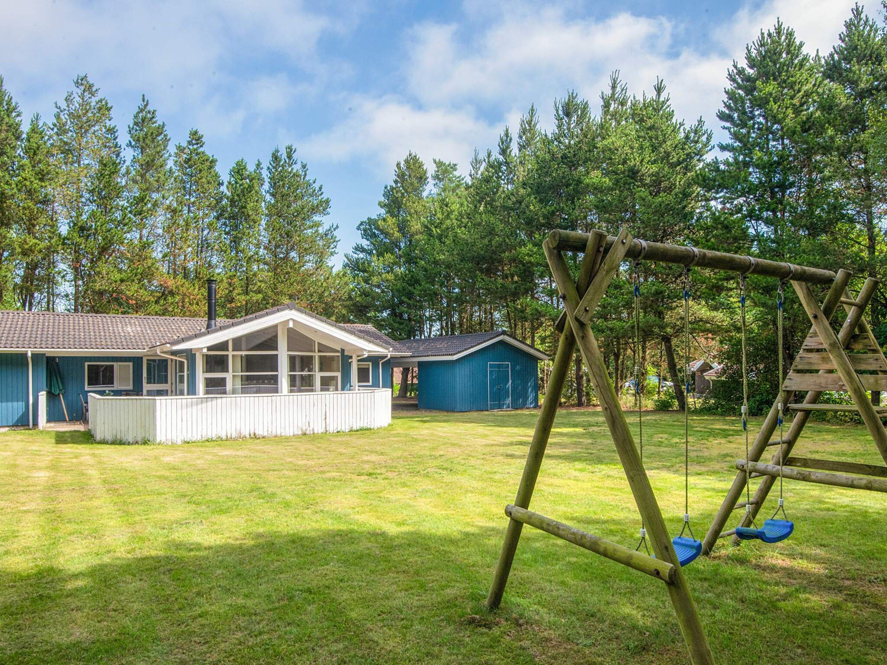 A residential property with a house, a garage, and a swing set in a grassy yard.