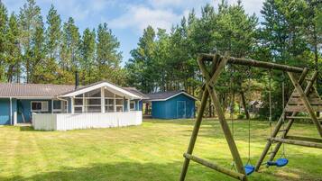 A residential property with a house, a garage, and a swing set in a grassy yard.