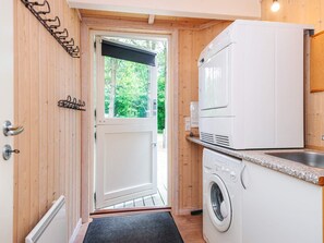Cocina compacta con lavadora, horno integrado y ventana con vistas a zonas verdes.