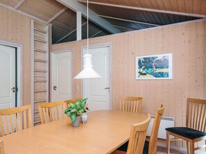 A dining area with a wooden table, chairs, a pendant light, and a painting on the wall.