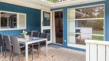 A patio with a table and chairs, a door leading to an interior space, and a window with a view of the outdoors.