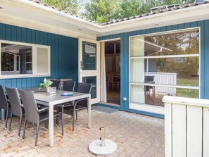 A patio with a table and chairs, a door leading to an interior space, and a window with a view of the outdoors.