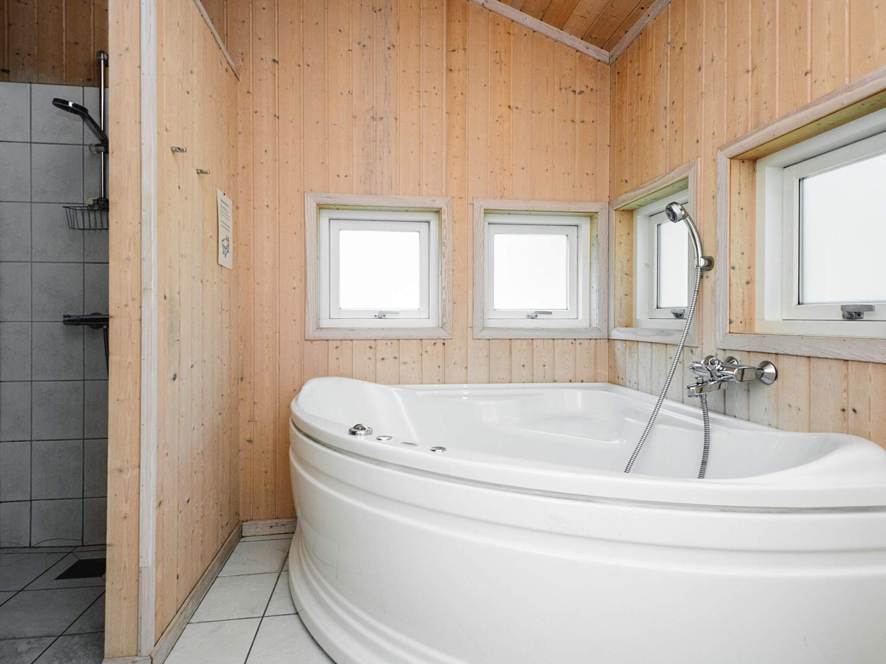 A bathroom with a freestanding bathtub, two windows, and a shower area.