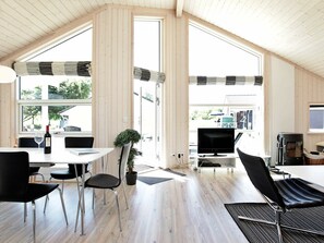 A modern, open-plan living space with a dining area, a seating area with a TV, and a fireplace.