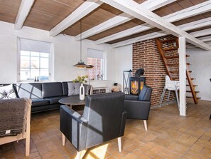 A modern living room with a fireplace, a sofa, a coffee table, and a staircase. - 9 Person Holiday Home in Harboore (Harboore)