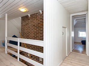 Une pièce avec un plancher en bois, un mur en briques et une rambarde blanche.