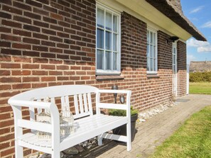 A brick house with a white bench and potted plants. - 9 Person Holiday Home in Harboore (Harboore)