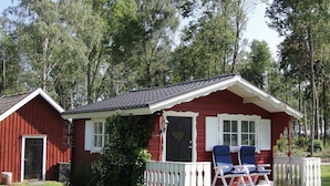 A red cabin with a porch, two chairs, and a small deck. - Holiday Home in Glesborg (Glanshammar)