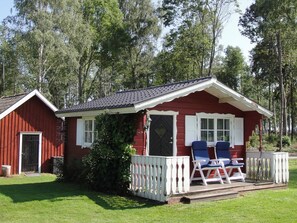A red cabin with a porch, two chairs, and a small deck. - Holiday Home in Glesborg (Glanshammar)