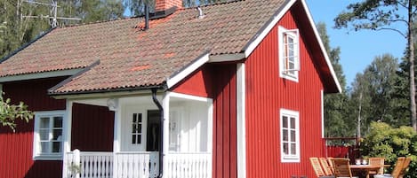 Una casa de madera roja con un porche blanco y una chimenea.