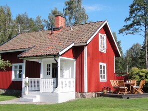 Une maison en bois rouge avec un porche blanc et une cheminée.