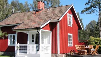 A red house with a white porch and a chimney.