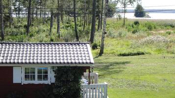 A house with a tiled roof, a white porch, and a view of a lake and forest.