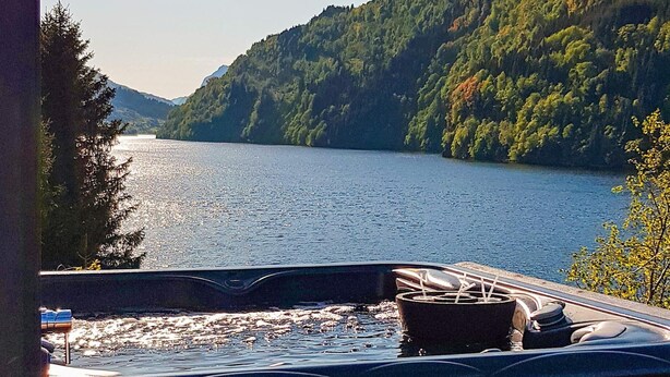 A hot tub with a view of a lake and forested hills. - 10 Person Holiday Home in Bygstad (Sunnfjord)