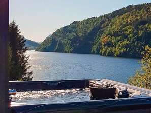 A hot tub with a view of a lake and forested hills. - 10 Person Holiday Home in Bygstad (Sunnfjord)
