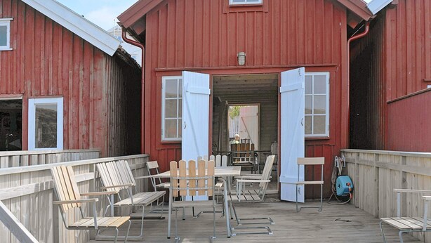 A red barn with a porch, wooden chairs, and a table. - Holiday Home in HÃ¤lleviksstrand (Hälleviksstrand)