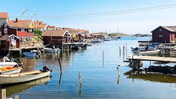 A harbor with boats docked, wooden houses, and a calm water body.