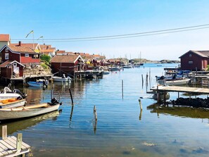 A harbor with boats docked, wooden houses, and a calm water body. - Holiday Home in Hälleviksstrand (Hälleviksstrand)