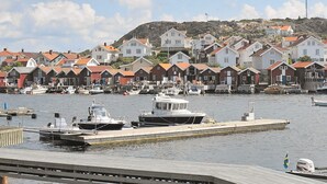 A harbor with boats docked, a pier, and a row of houses with red roofs. - Holiday Home in HÃ¤lleviksstrand (Hälleviksstrand)