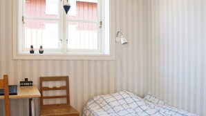 A room with a bed, a desk, a chair, a window, and a wall-mounted lamp. - Holiday Home in HÃ¤lleviksstrand (Hälleviksstrand)